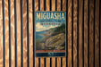A vintage-style metal sign for the MIGUASHA NATIONAL PARK, Canada, featuring a scenic landscape with a rocky coastline, trees, and a body of water.
