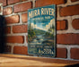 A vintage-style metal sign for Mira River Provincial Park in Nova Scotia, featuring a scenic landscape with a river, mountains, and pine trees.