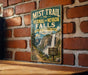 A vintage-style metal sign for the Mist Trail to Vernal and Nevada Falls in Yosemite National Park, California, mounted on a brick wall.