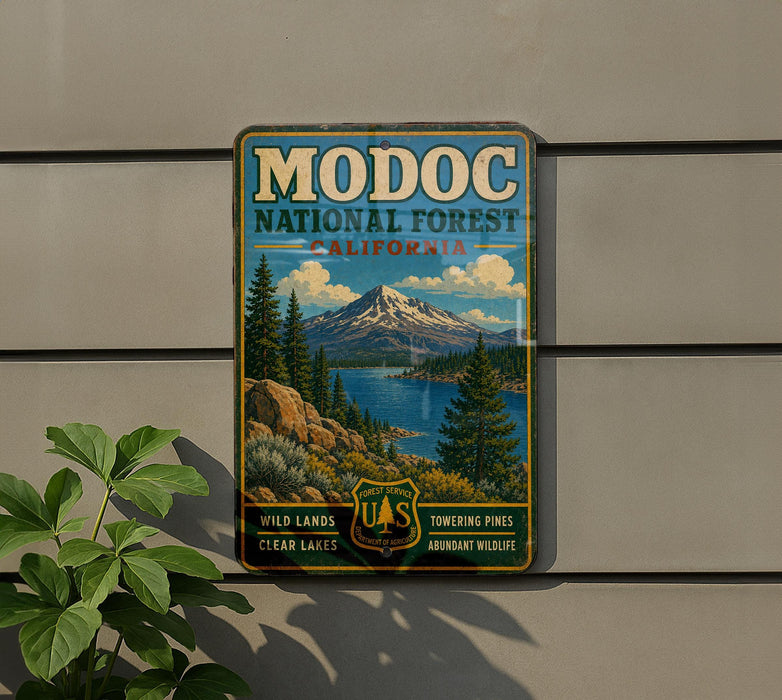 A vintage-style metal sign for Modoc National Forest, California, featuring a mountain landscape with pine trees and clear lakes.