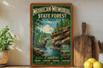 A vintage-style sign for the Mohican-Memorial State Forest in Ohio, featuring a scenic illustration of a river, trees, and a bridge.