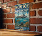 A vintage-style metal sign for the Monitor National Marine Sanctuary in North Carolina, featuring an illustration of a submarine and marine life.