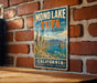 A vintage-style metal sign for the Mono Lake Tufa State Natural Reserve in California, featuring a scenic landscape with mountains and a lake.