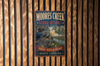 A vintage metal sign for Moore's Creek National Battlefield, featuring a historical illustration of soldiers and a river, mounted on a wooden wall.