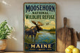 A vintage-style metal sign for Moosehorn National Wildlife Refuge in Maine, featuring an illustration of a moose in a natural setting.