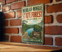 A vintage-style metal sign for Morgan-Monroe State Forest, Indiana, featuring a scenic image of a forest and a lake.