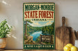 A vintage-style sign for Morgan-Monroe State Forest, Indiana, featuring a scenic landscape with a lake and trees.