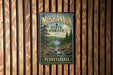 A vintage metal sign for the Moshannon State Forest in Pennsylvania, featuring a scenic illustration of a forest and a river.