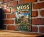 A vintage-style metal sign for the Moss mansion in Billings, Montana, featuring an illustration of the mansion and text promoting its historical and scenic attractions.