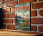 A vintage-style sign for Mount Assiniboine Provincial Park in British Columbia, Canada, featuring a scenic mountain landscape.