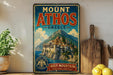 A vintage-style metal sign for Mount Athos in Greece, featuring a castle on a cliff overlooking the sea.