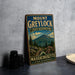 A vintage metal sign for Mount Greylock State Reserve in Massachusetts, featuring a scenic mountain landscape with pine trees and a trail.