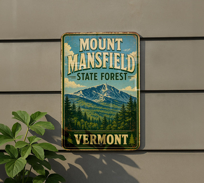 A vintage metal sign for Mount Mansfield State Forest in Vermont, featuring a mountain landscape and pine trees.