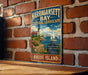 A vintage metal sign for Narragansett Bay, New Hampshire, featuring a lighthouse and a sailboat on the water.