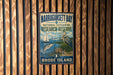 A vintage-style metal sign for Narragansett Bay National Estuarine Research Reserve, featuring a sailboat, a crane, and a bird, is displayed on a wooden wall.