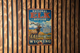 A vintage metal sign for the National Elk Refuge in Wyoming, featuring an illustration of a majestic elk standing in a scenic landscape with mountains in the background.