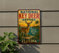 A vintage-style metal sign with a deer illustration, mounted on a wall with a plant in the foreground.