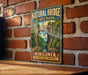 A vintage-style metal sign for the Natural Bridge State Park in Virginia, featuring a scenic landscape with a bridge and water.