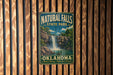 A vintage-style metal sign for Natural Falls State Park in Oklahoma, featuring a waterfall and lush greenery.