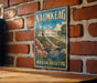 A vintage metal sign for Naimkeag Estate in Massachusetts, featuring a scenic illustration of a building surrounded by a garden and a pond.