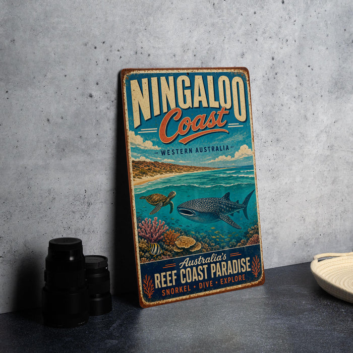 A vintage-style metal sign for the Ningaloo Coast in Western Australia, featuring an illustration of a whale, coral, and other marine life.