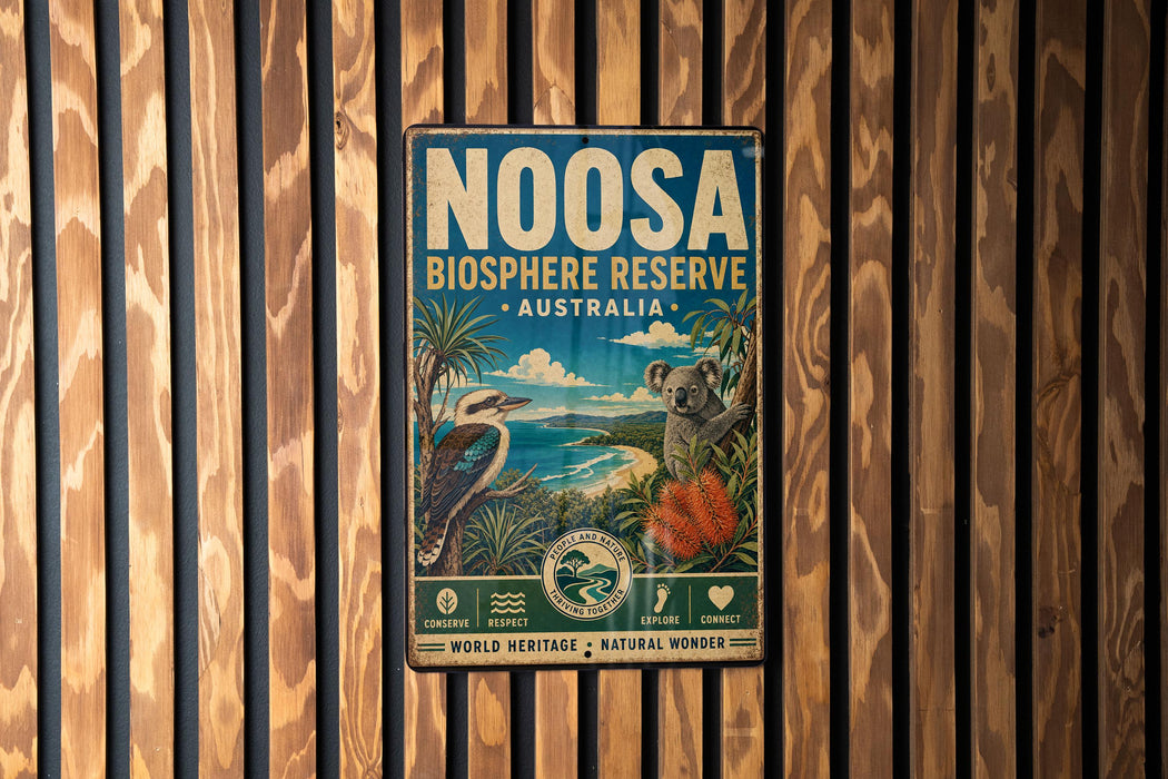 a vintage-style metal sign with a koala and a bird, mounted on a wooden wall.