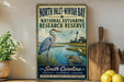 A vintage-style sign for the North Inlet-Win yacht bay in South Carolina, featuring a blue heron and a lighthouse in the background.