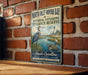 A vintage-style metal sign for the North Inlet-Winyah Bay National Estuarine Research Reserve in South Carolina, featuring an illustration of a heron and a lighthouse.