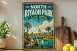 A vintage-style metal sign for North Riyadh Park in Saudi Arabia, featuring a scenic illustration of a park with palm trees, a river, and a tent-like structure.