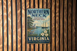 A vintage metal sign for the Northern Neck National Heritage Area in Virginia, featuring a sailboat and a lighthouse, mounted on a wooden wall.