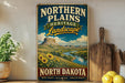 A vintage-style sign advertising the Northern Plains Heritage Landscape in North Dakota, featuring a scenic landscape with a mountain, river, and sunflowers.