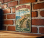 A vintage-style metal sign for Northumberland Provincial Park hangs on a brick wall, featuring a scenic image of a wooden walkway leading to a beach.