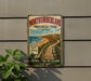 A vintage-style sign for Northumberland Provincial Park, featuring a scenic beach and pathway, mounted on a wall next to a plant.