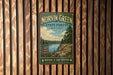 A vintage metal sign for Norvin Green State Forest in New Jersey, featuring a scenic landscape with a lake, mountains, and pine trees.