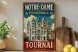 A vintage-style metal sign for Notre-Dame Cathedral in Beloique, Belgium, featuring an illustration of the cathedral and the text "NOTRE-DAME CATEDRALE TOURNAI BELOIQUE".