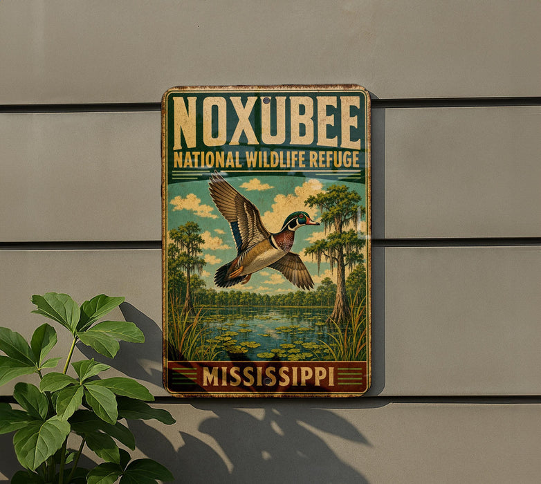 A vintage-style metal sign for the Noxubee National Wildlife Refuge in Mississippi, featuring a colorful illustration of a bird in flight over a pond.