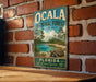 A vintage-style metal sign for the Ocala National Forest in Florida, featuring a scenic landscape with a turtle in the foreground.