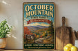 a vintage-style sign for October Mountain State Forest in Massachusetts, with a scenic mountain landscape and a sign inviting visitors to explore the forest.
