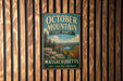A vintage metal sign for October Mountain State Forest in Massachusetts, featuring a scenic landscape with mountains, forests, and a river.