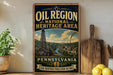 A vintage-style sign for the Pennsylvania Oil Region National Heritage Area, featuring an illustration of a coal mine and a river, with the text "Pennsylvania" and "Our Heritage Fuels Our Future" at the bottom.
