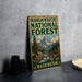 A vintage-style sign for the Okanogan-Wenatchee National Forest in Washington, featuring a mountain landscape and a river.