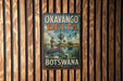 A vintage-style metal sign for Okavango Delta, Botswana, featuring a man in a boat on a river surrounded by wildlife.