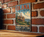 A vintage-style metal sign for the Olana State Historic Site in New York, featuring an illustration of a historic building and landscape.