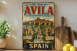 a vintage-style metal sign advertising the Old Town of Avila, Spain, with its picturesque churches and architecture.