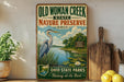 a vintage-style sign for Old Woman Creek State Nature Preserve in Ohio, with a large blue heron in the foreground and a scenic landscape in the background.