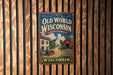 A vintage-style metal sign for "Old World Wisconsin" hanging on a wooden wall.