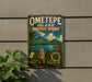 A vintage-style metal sign for Ometepe Island, Biosphere Reserve, and Nicaragua, featuring a tropical landscape with mountains, palm trees, and a statue.