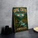 A vintage metal sign for Opal Creek Scenic Recreation Area in Oregon, featuring a scenic mountain landscape with a river flowing through it.