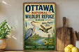 A vintage-style metal sign for the Ottawa National Wildlife Refuge in Ohio, featuring illustrations of birds and a scenic landscape.