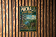 A vintage-style metal sign for the Pachaug State Forest in Connecticut, featuring a scenic image of a forest and a lake.